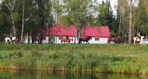 a group of people riding horses in front of a barn at Zirgu sēta "Klajumi" - Horse ranch "Klajumi" in Kaplava