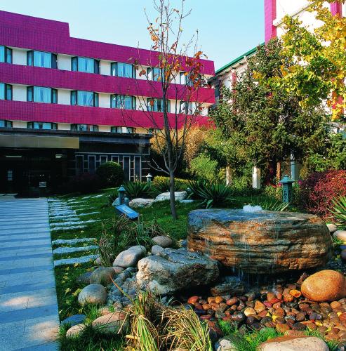 a fountain in a garden in front of a building at Xijiao Hotel Beijing in Beijing