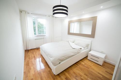 Habitación blanca con cama y espejo en Bor Apartment en Bor