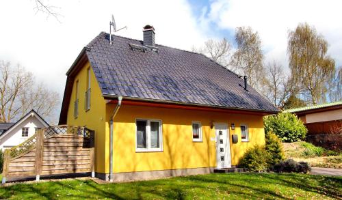 a yellow house with a black roof at Ferien_HAUS SEEBRISE in Göhren-Lebbin