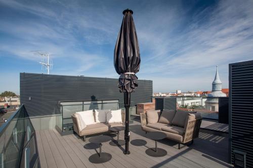a patio with two chairs and an umbrella on a roof at Ilonn Boutique Limanowskiego in Poznań