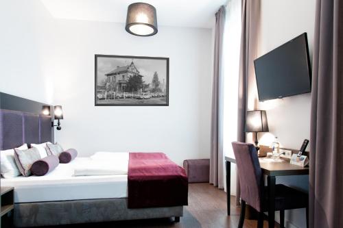 フランクフルト・アム・マインにあるArena an der Friedberger Warteのベッドとデスクが備わるホテルルームです。