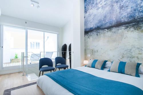 a bedroom with a bed and two blue chairs at City Center Atico 360 in Valencia