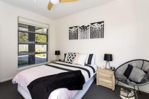 a bedroom with a bed and a chair and a window at Windella Escape in Rosebud