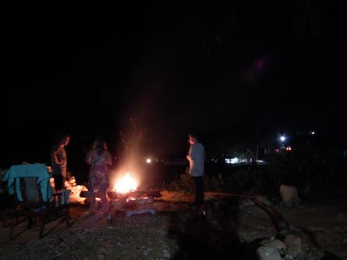 a group of people standing around a fire at night at Deniyaya National backpackers hostel in Deniyaya