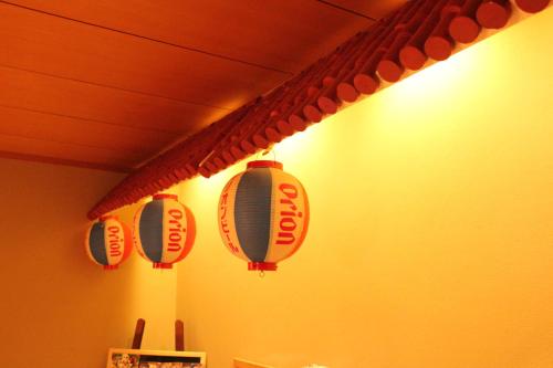 a group of lanterns hanging on a wall at Okinawa Minshuku Kariyushi in Shirahama