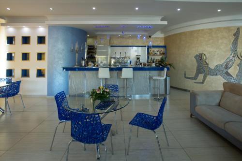 a dining room with a glass table and blue chairs at Hotel The Queen in Pastorano