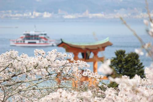 una pagoda e una barca in acqua con fiori rosa di Guesthouse COCO Hiroshima (Female Only) a Hiroshima