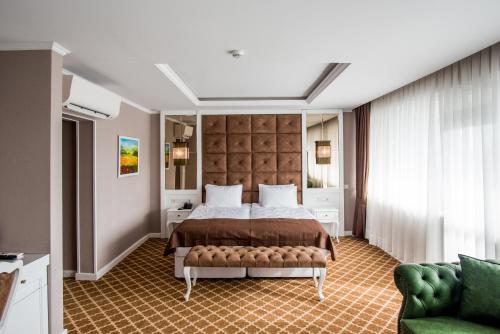 een slaapkamer met een groot bed en een groene bank bij Hotel Arpezos in Kŭrdzhali