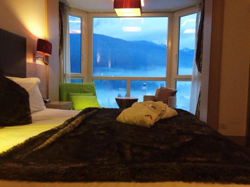 a bedroom with a bed with a large window at Antelao Dolomiti Mountain Resort in Borca di Cadore