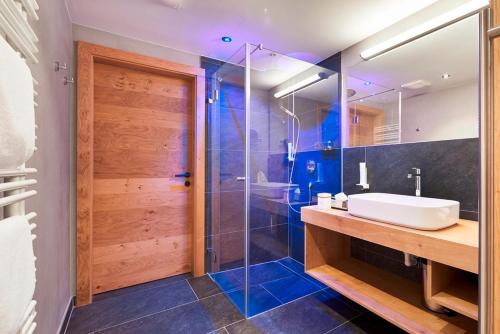 a bathroom with a sink and a glass shower at Bauernhof Hotel Oberschwarzach in Saalbach Hinterglemm