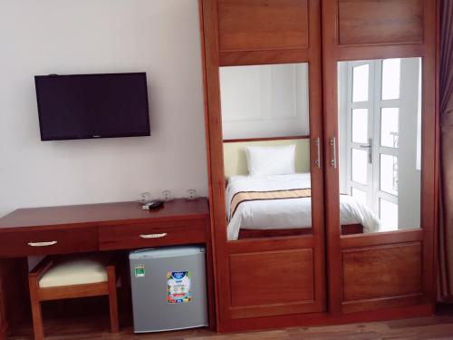 a bedroom with a sliding door with a bed and a desk at Queen Hotel in Quy Nhon