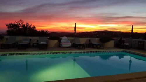 a swimming pool with a sunset in the background at Felicidade in Loulé