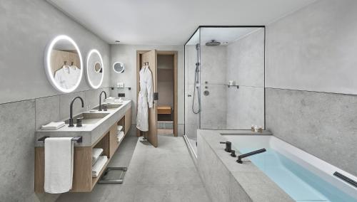 a bathroom with two sinks and a tub and a shower at Hotel Weisses Roessl in Kitzbühel