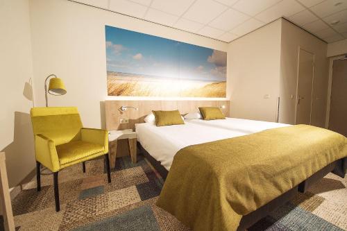 a hotel room with two beds and a yellow chair at Hotel Bornholm in West-Terschelling