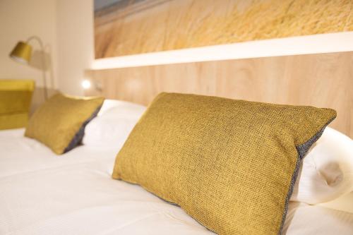 a bed with a yellow pillow on top of it at Hotel Bornholm in West-Terschelling