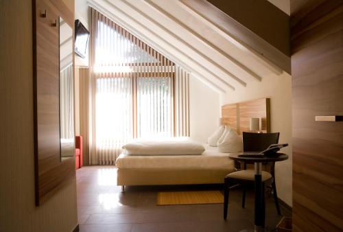 a bedroom with a bed and a window and a desk at Parkhotel Lindau in Lindau