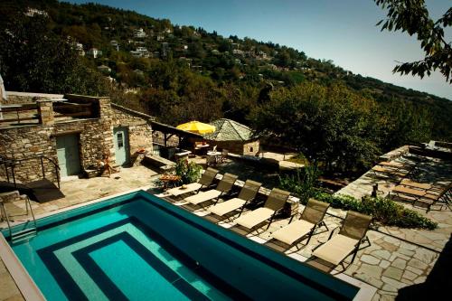 uma piscina com cadeiras e uma casa em Archontiko Stathopoulou em Agios Georgios Nilias