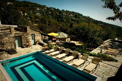 a swimming pool with chairs and a house at Archontiko Stathopoulou in Agios Georgios Nilias