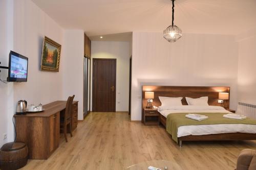 Dormitorio con cama, escritorio y TV en Hotel King Tom en Tiflis