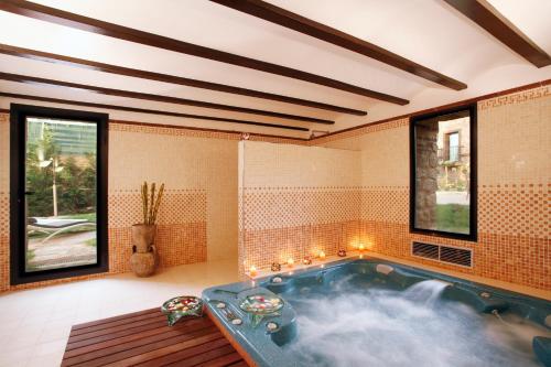 eine Whirlpool-Badewanne in einem Zimmer mit Fenstern in der Unterkunft Hotel Boutique Real Casona De Las Amas in Azofra