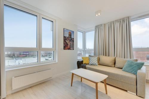 a living room with a couch and large windows at Chrobry Apartamenty Gdańsk Grodzka 10 in Gdańsk