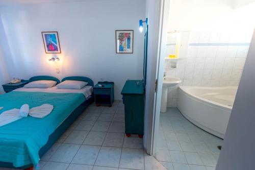 a bedroom with a bed and a tub and a sink at Caldera View Resort - Adults Only in Akrotiri