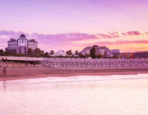 a beach with chairs and buildings in the background at Melas Lara Hotel in Lara