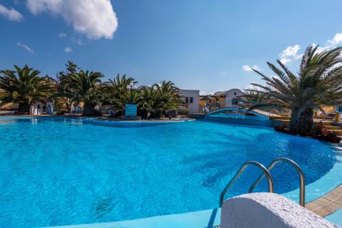 a large swimming pool with palm trees in a resort at Caldera View Resort - Adults Only in Akrotiri