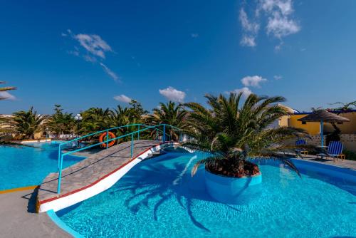 a resort pool with a slide and a palm tree at Caldera View Resort - Adults Only in Akrotiri