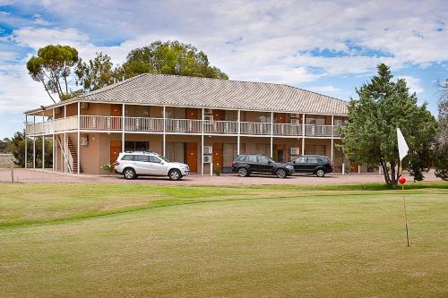 a large building with two cars parked in front of it at Standpipe Golf Motor Inn in Port Augusta