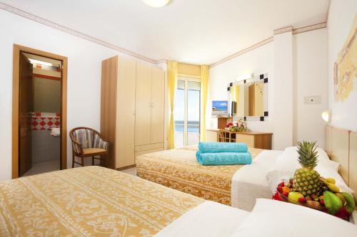a hotel room with two beds with fruit on top of them at Hotel Caesar in Cesenatico