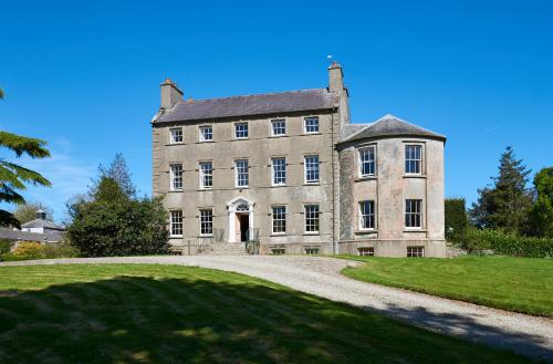 an old stone house with a driveway in front at Ballydugan Country House in Downpatrick