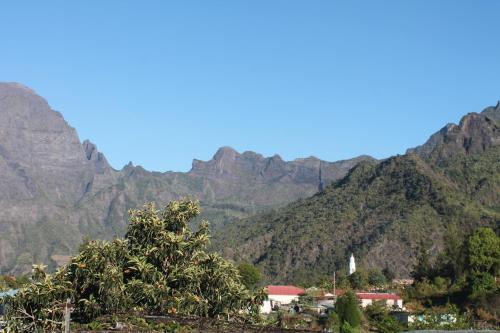 a mountain view of a village in front of mountains at les cases prés du lac in Cilaos