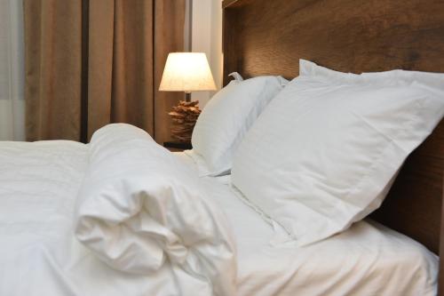 1 cama no hecha con sábanas y almohadas blancas en Hotel King Tom, en Tiflis