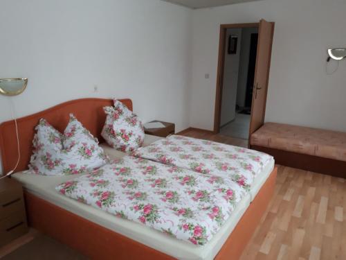 um quarto com uma cama com lençóis e almofadas florais em Ferienwohnung em Reinhardtsdorf