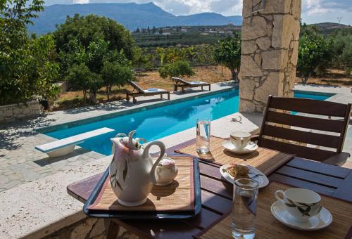 a wooden table with a tea set on it next to a pool at Panorama Villa Private Pool, BBQ, Parking in Sitia