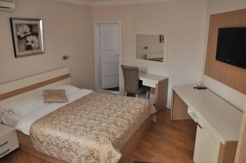 a bedroom with a bed and a desk and a television at Hotel Prima in Pristina