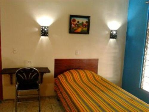 a bedroom with a bed and a desk and two lights at Hostal Doña Marta in San Salvador