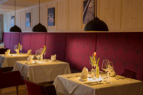 a dining room with two tables with white table cloths at Hotel Kanisfluh in Mellau