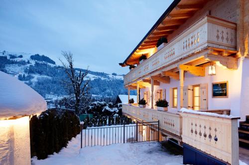 a house with a balcony in the snow at Tennerhof Luxury Chalets in Kitzbühel