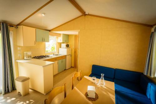 a small kitchen with a table and a blue couch at Aloha Camping Club in Reynès
