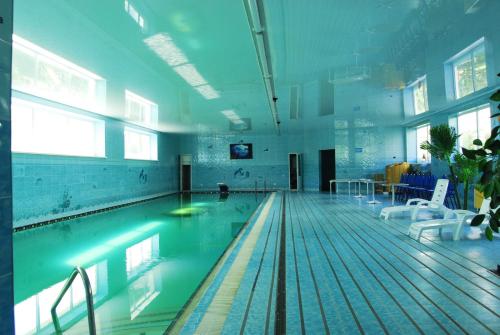 a large swimming pool with chairs in a large room at Gostinitsa "Sultan" in Aktobe