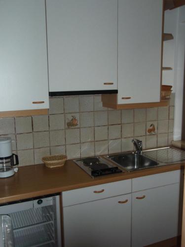 Una cocina con gabinetes blancos y un fregadero. en Klaus Prettau, en Predoi