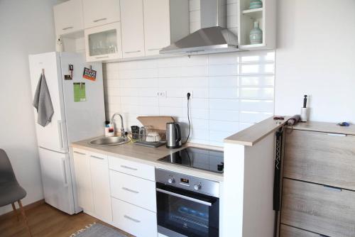 a small kitchen with white cabinets and a refrigerator at Bardolino Apartment in Belgrade