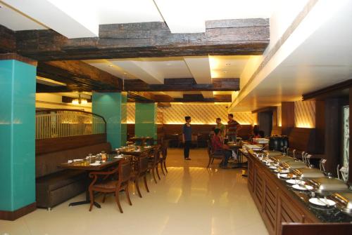 a restaurant with tables and chairs and people standing in a room at Grand Heritage Narmada Jacksons in Jabalpur