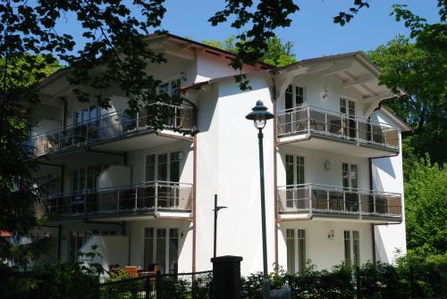 オストゼーバート・ゼリンにあるStrandwohnungen Sellin - WG02 mit Terrasseのバルコニーと通りの明かりが付く白い建物