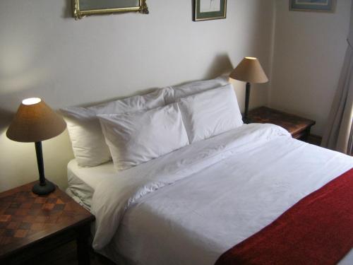 Ladismith Manor في لاديسميث: غرفة نوم بسرير ذو شراشف ووسائد بيضاء