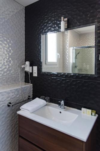a bathroom with a white sink and a mirror at Logis Grand Hotel Pelisson in Nontron