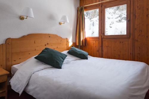 a bedroom with a white bed with two green pillows at travelski home select - Résidence Les Chalets du Galibier 4 stars in Valloire